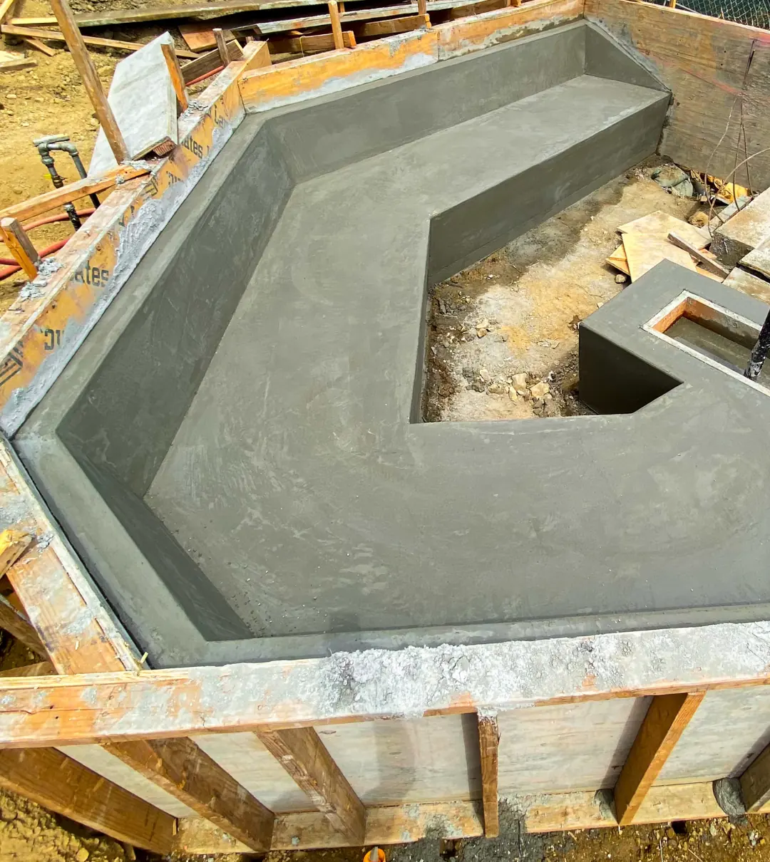 Cast concrete bench curing inside its forms, its angled seat and fire-feature base now visible