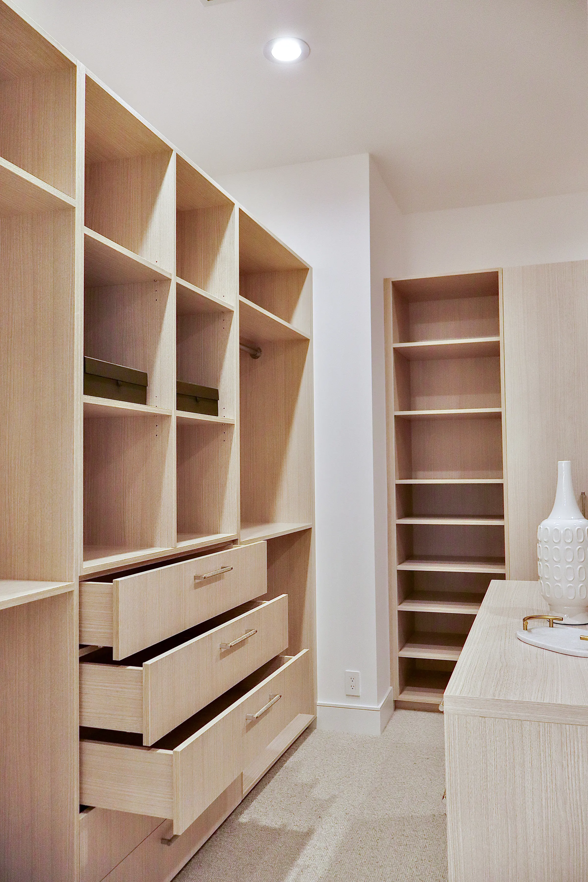 Oak closet drawers pulled open beneath open cubbies, with a shoe tower beyond