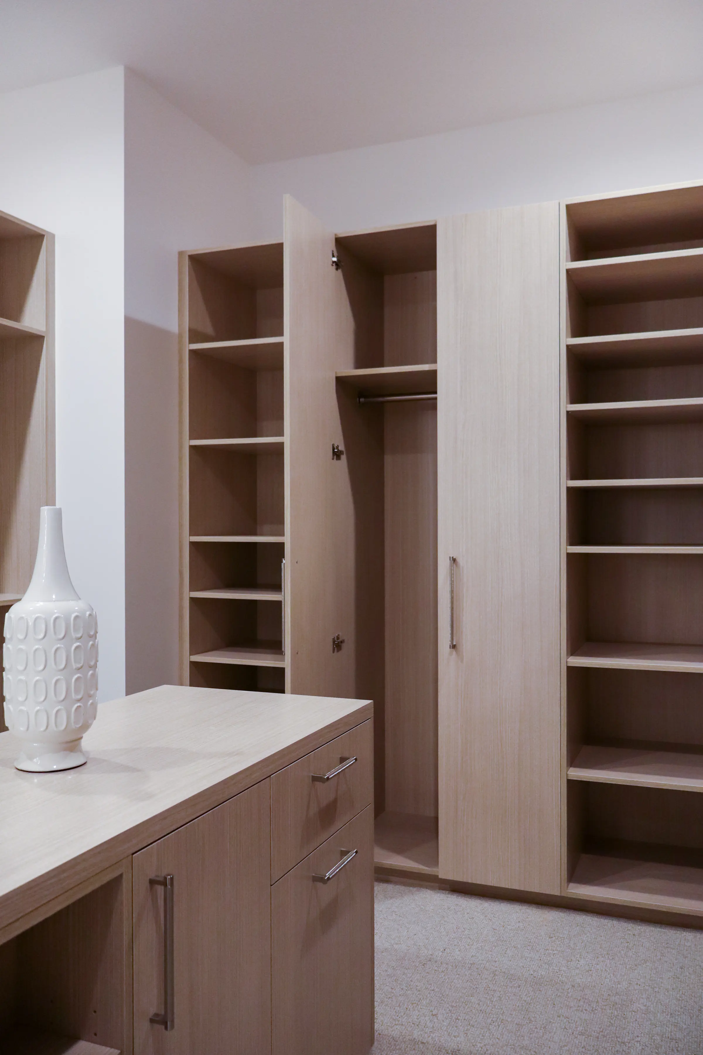 Closet island beside full-height wardrobes, one door open to a hanging rail