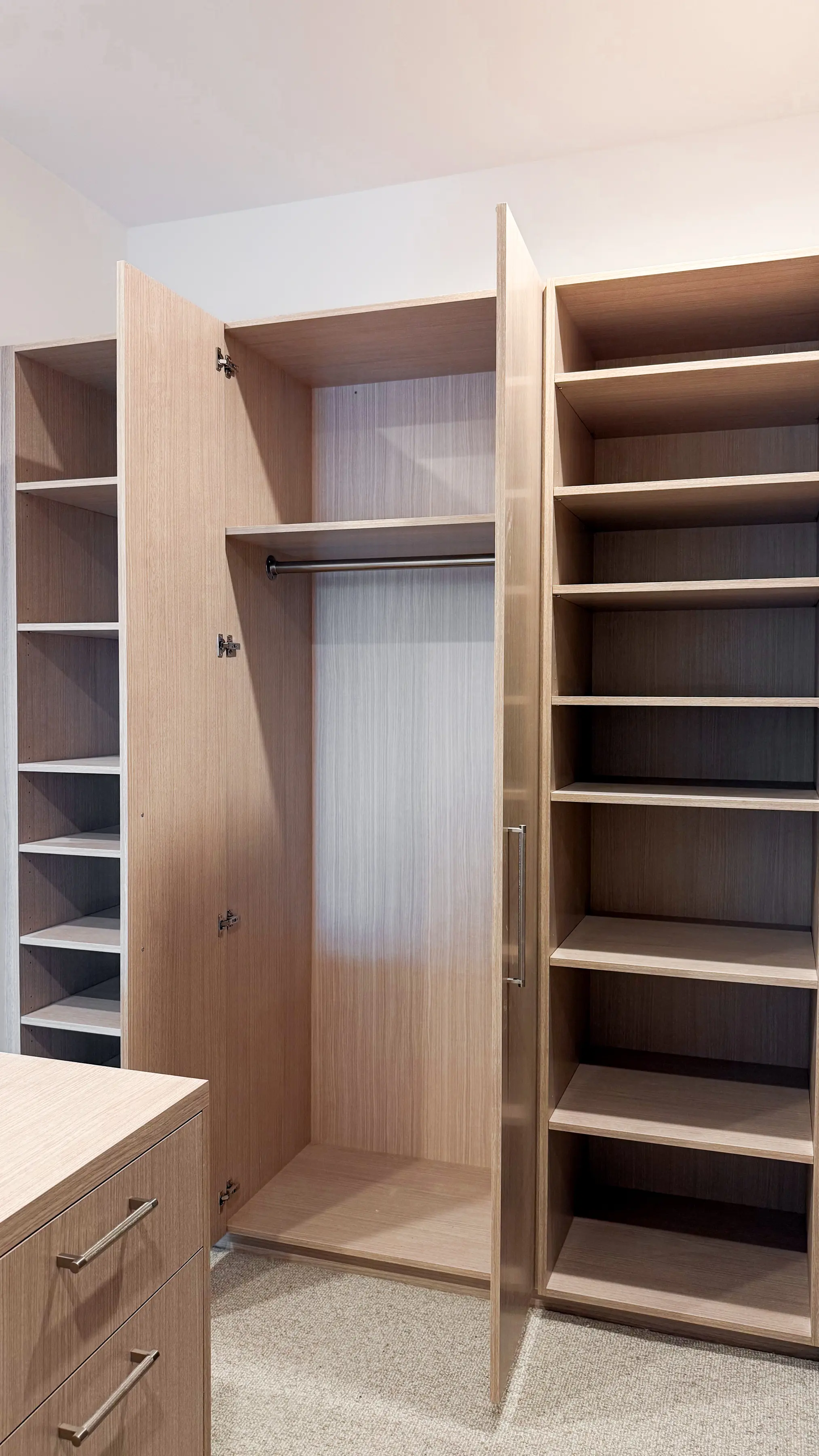 Open oak wardrobe with a hanging rail between two full-height shelving towers