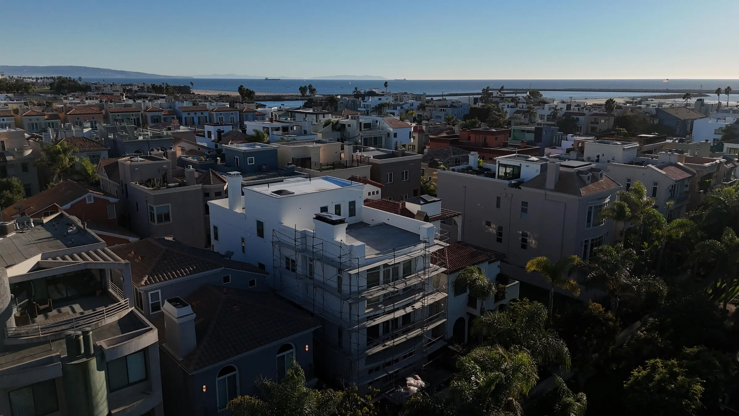 Aerial view of the Marina del Rey residence under scaffolding during its renovation, with the ocean beyond