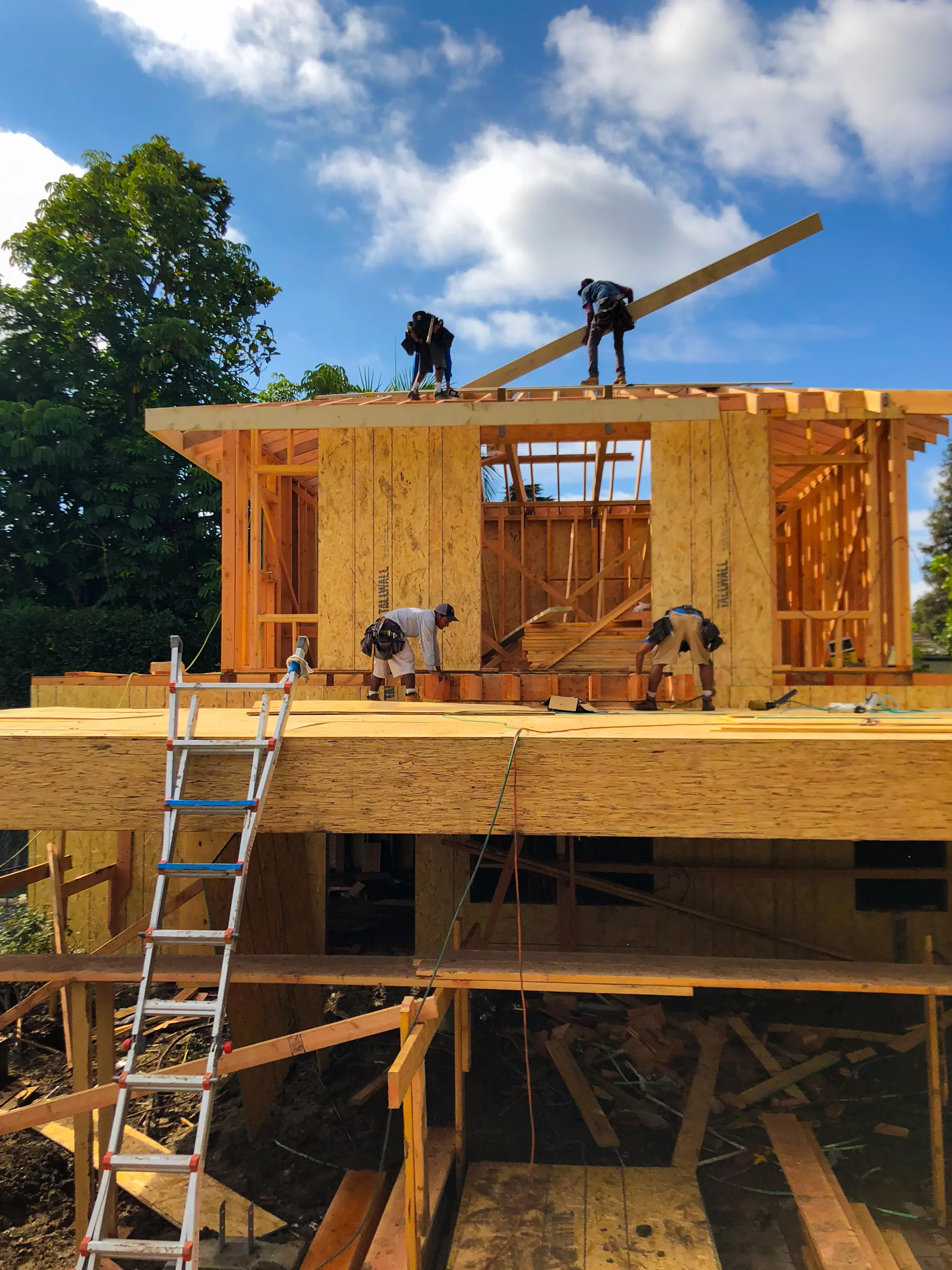Framing crew setting roof members on a two-story wood frame against a blue sky