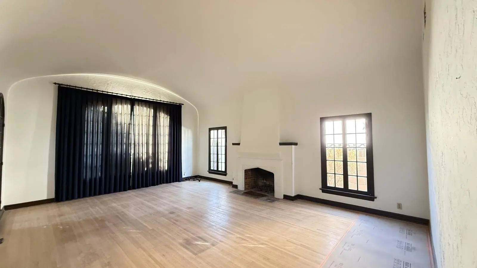 Finished living room with light wood flooring, a fireplace and arched windows