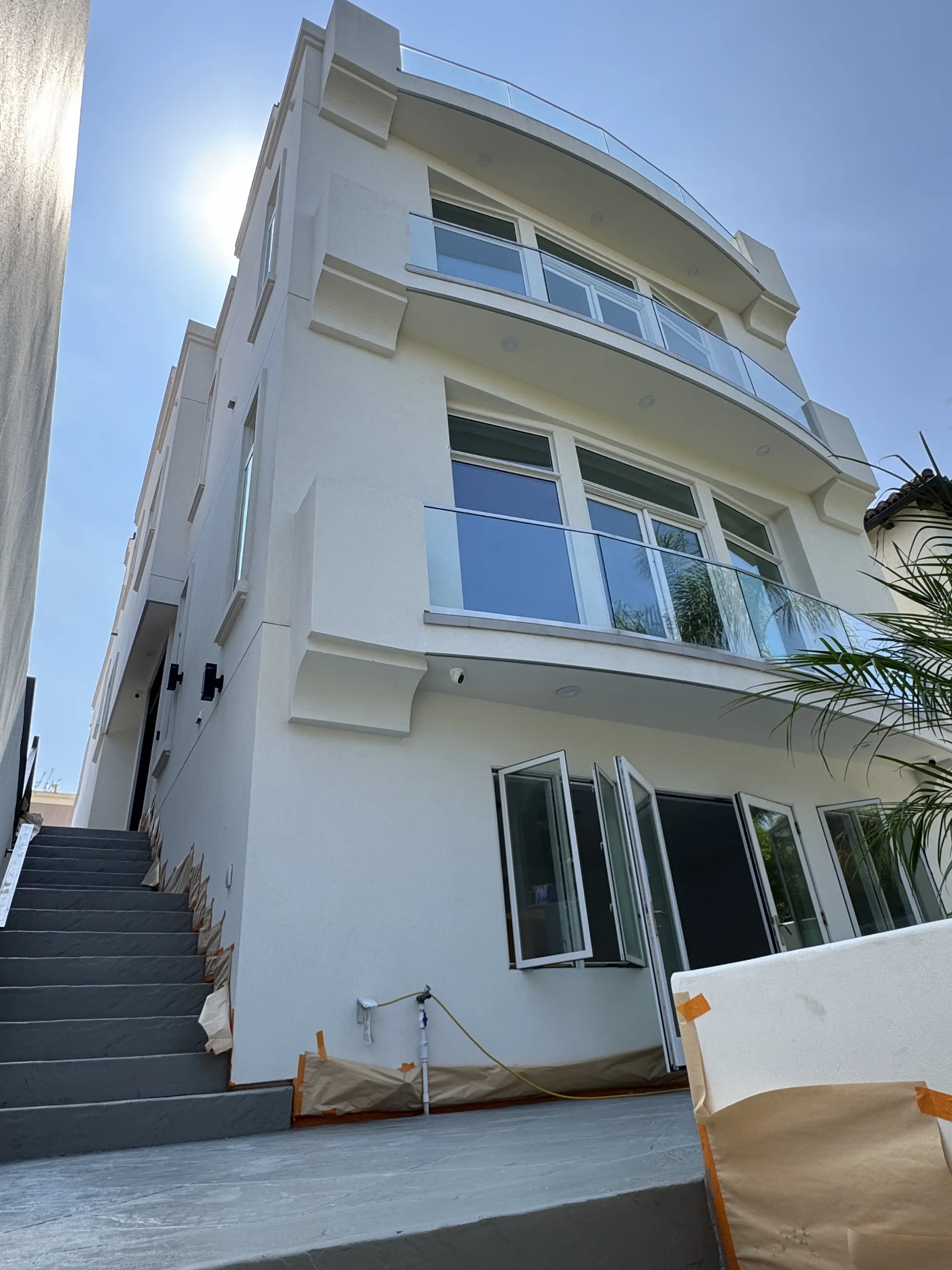 Exterior after the remodel: a smooth white façade with curved glass balconies and new windows