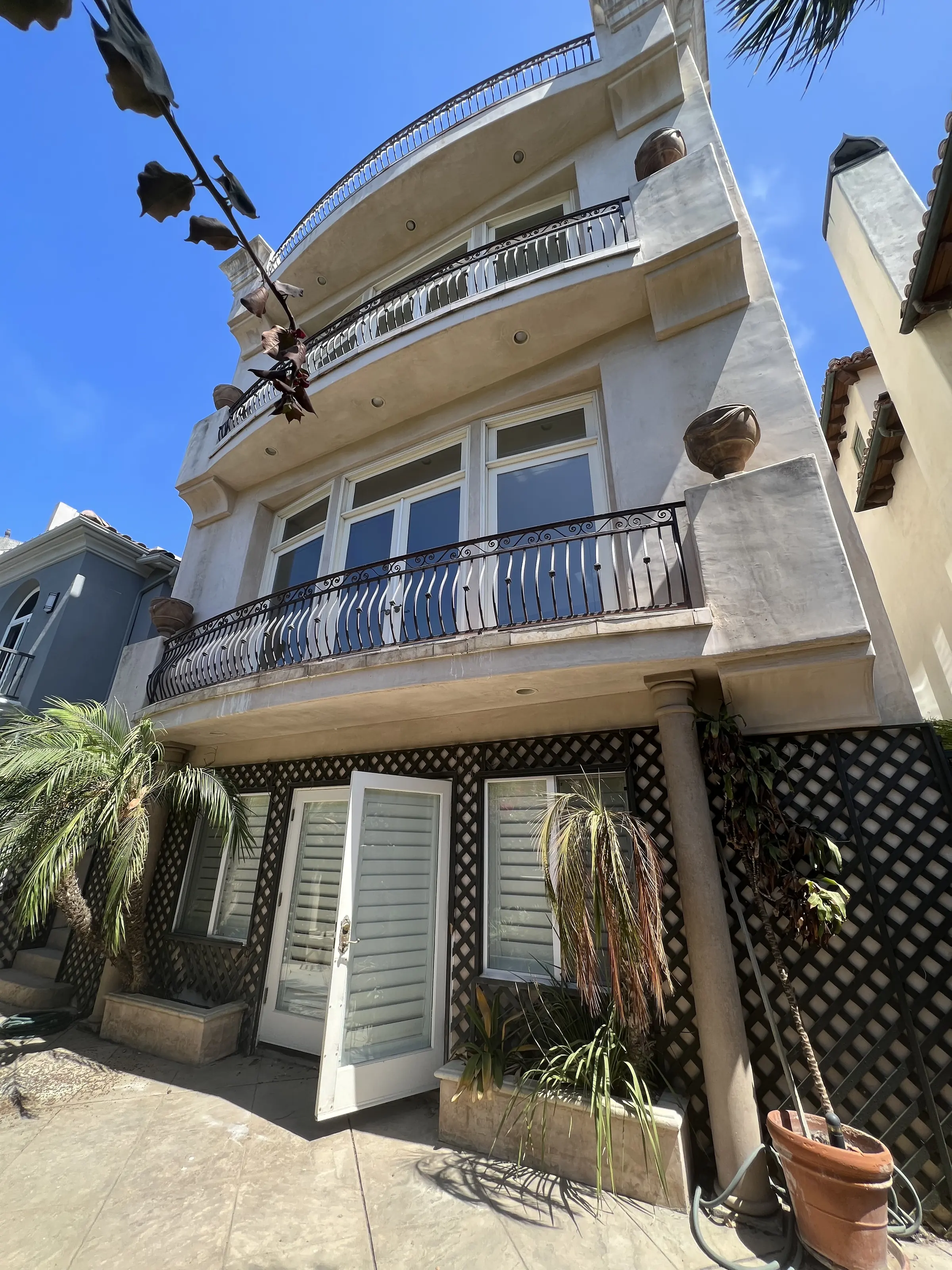 Exterior before the remodel: a Mediterranean façade with wrought-iron balconies, lattice screens and terracotta details