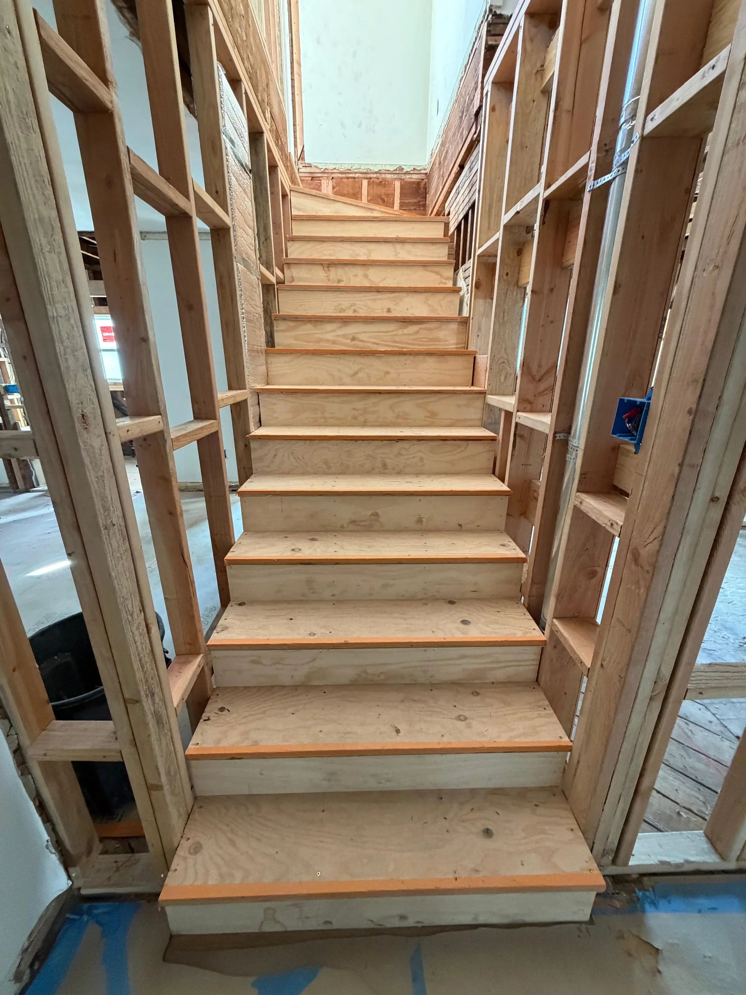 Timber stair framed between new stud walls during a remodel